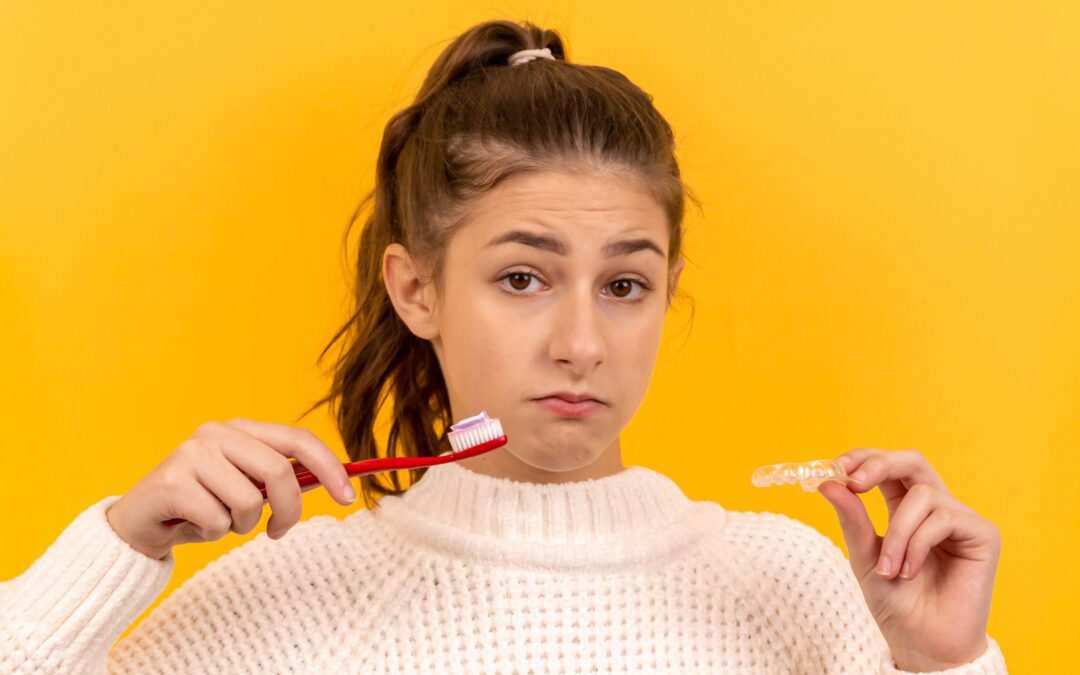 girl holding toothbrush and aligner