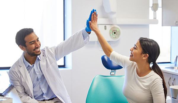 Dentist, patient and happy with high five for celebration or success of teeth whitening, oral and dental care. Male doctor, woman and together for well done or good job, support and consultation. Dr. Peter Servinis